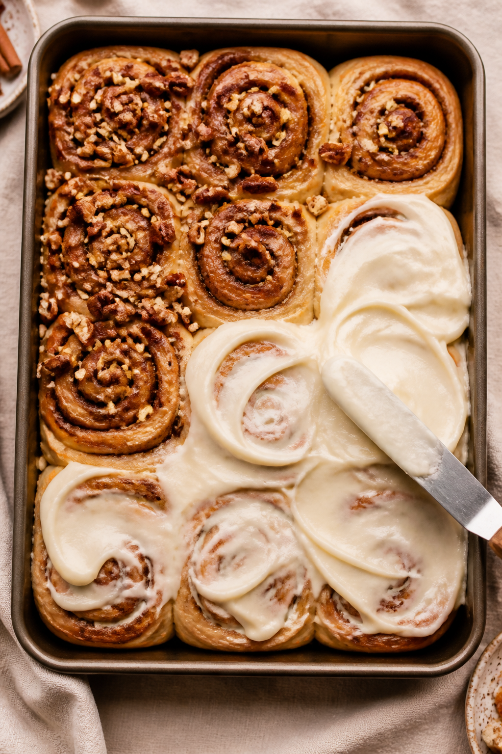 Overhead shot of a 9x13 pan of freshly baked carrot cake cinnamon rolls just out of the oven, lightl