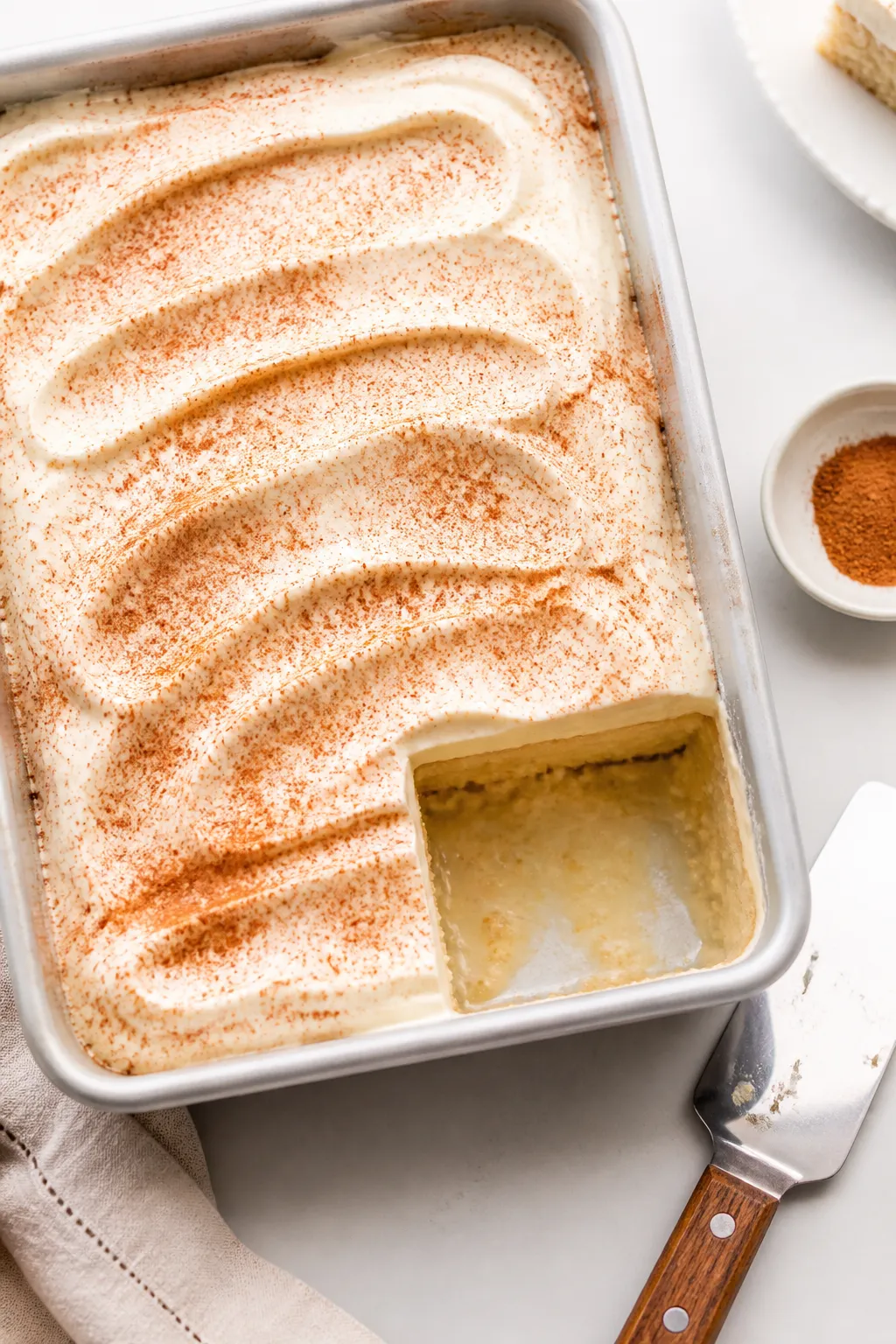 Overhead “tasty top view”: Chilled tres leches cake in the pan, blanketed with smooth, cloud-lik