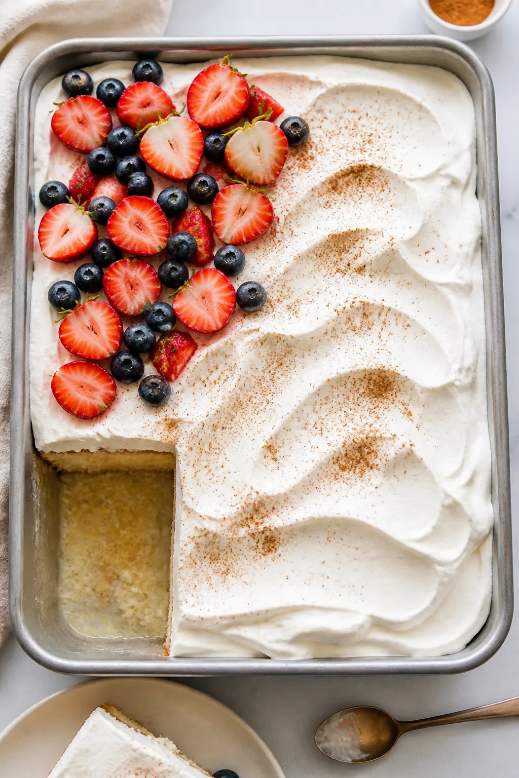 Overhead “tasty top view” of the fully finished tres leches cake in the pan: smooth billows of s