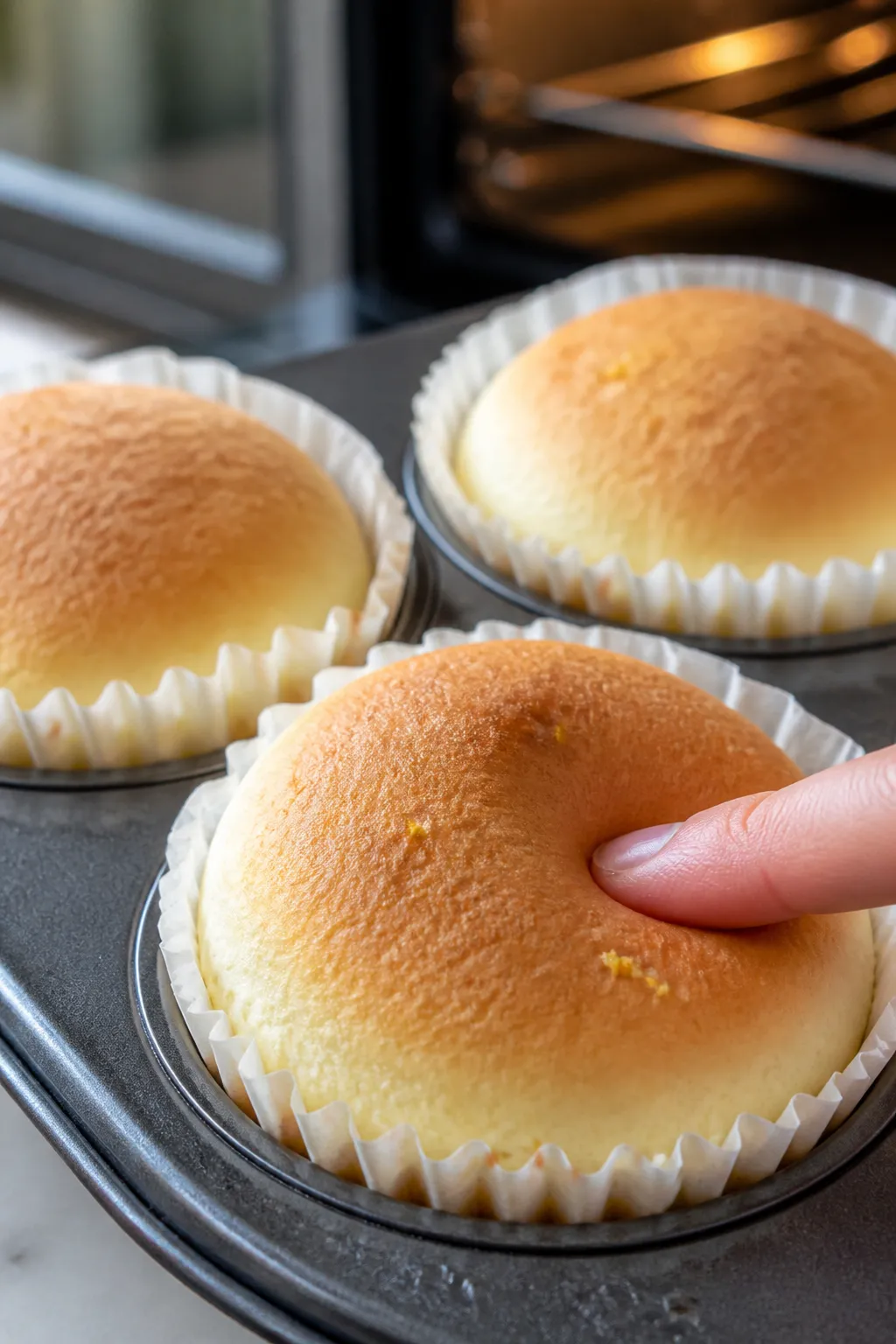 Close-up detail: A trio of freshly baked Japanese cotton cheesecake cupcakes just out of the oven, t