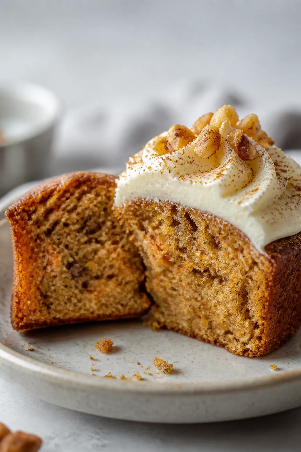 Close-up detail shot: A freshly baked gluten-free carrot cake cupcake sliced in half to reveal a ten