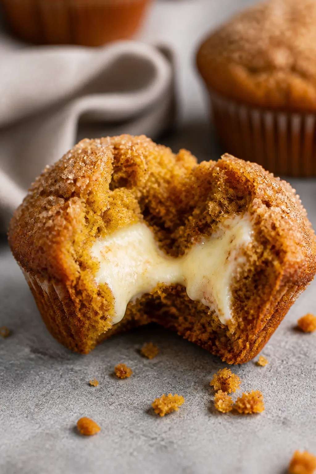 Close-up detail shot of a freshly baked Pumpkin Cream Cheese Muffin torn open to reveal the silky, t