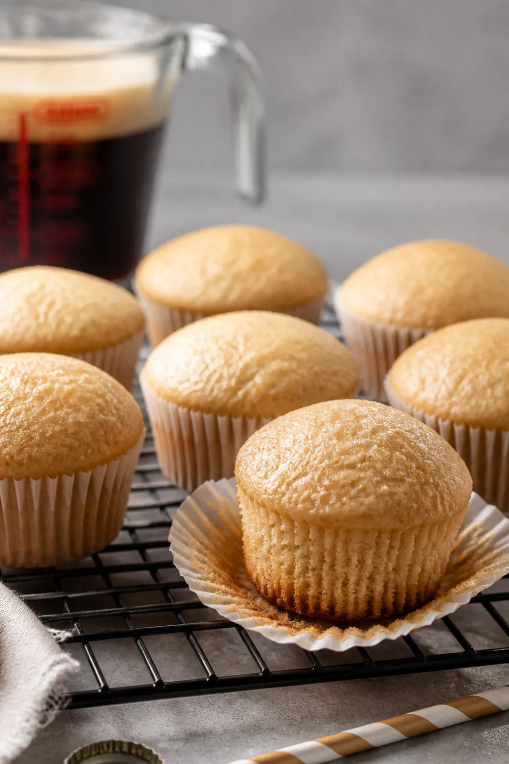 Cooking process close-up: Just-baked root beer float cupcakes cooling on a wire rack, golden domed t