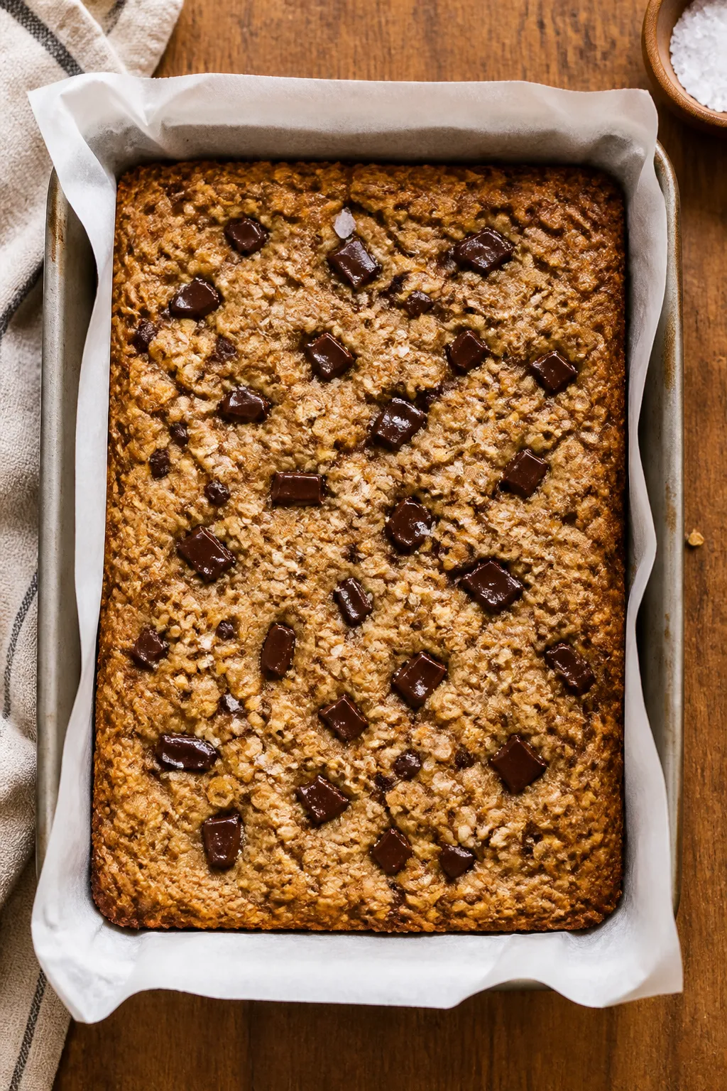 Overhead shot of freshly baked chewy oatmeal bars in a parchment-lined 9x13 pan just out of the oven